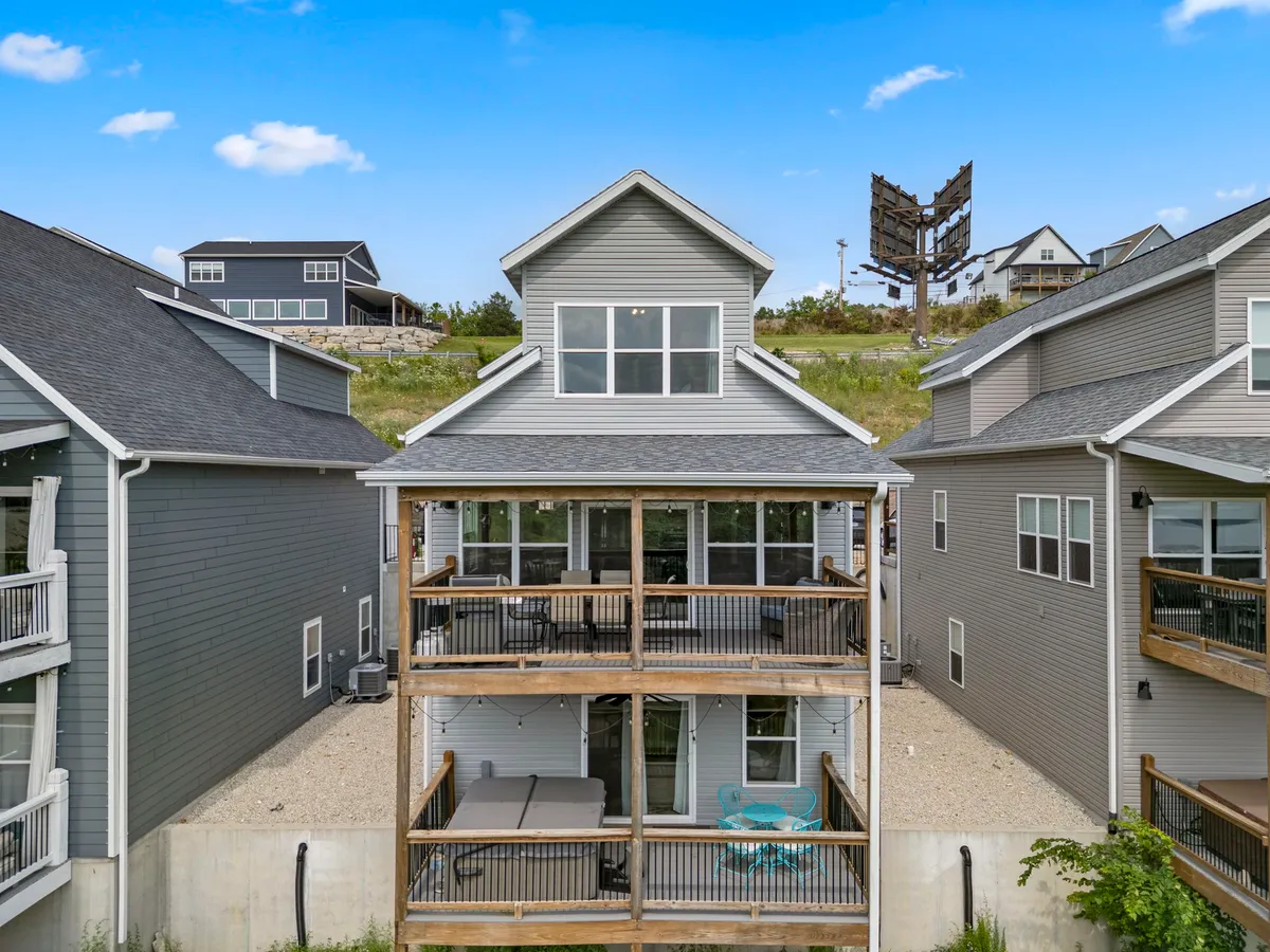 A multi-level deck with modern architectural lines overlooks serene lake views and natural landscaping. The deck is furnished for relaxing and dining, inviting guests to step outside and enjoy the panorama.