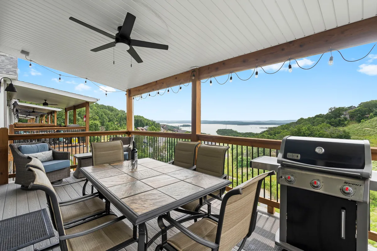 A scenic exterior of a spacious outdoor dining area with a grill, comfortable seating, and a beautiful view of the lake beyond. The scene suggests relaxation after a day of adventure, with plenty of space for pets and people to unwind together.