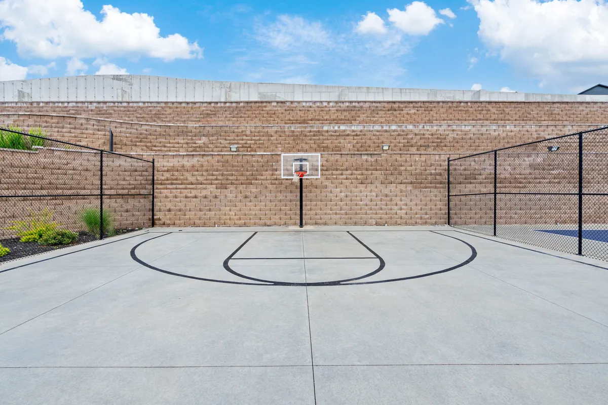 A focused view of the basketball court, featuring a hoop and clear court lines surrounded by a chain-link fence. The court is ready for casual games or competitive matches, inviting active family recreation.