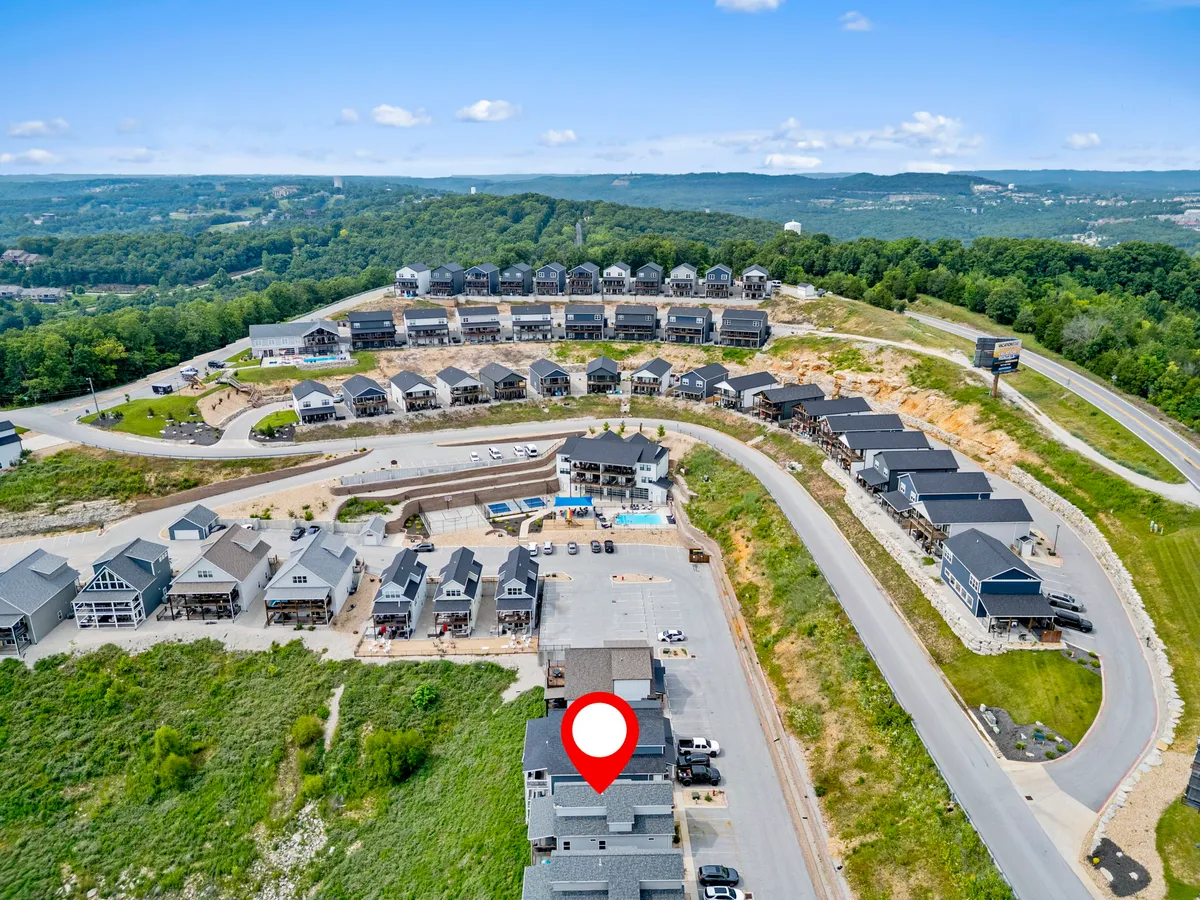 This exterior image captures rows of houses in a landscaped resort community, a swimming pool, and winding roads bordered by greenery. The open, communal spaces are welcoming and safe for leisurely strolls, perfect for guests with dogs.