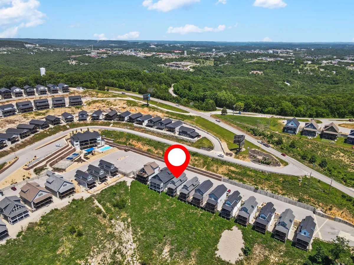 An exterior shot featuring newly constructed homes, winding roads, and lush surrounding greenery, with a distant cityscape visible. The calm, expansive setting reflects both community amenities and natural spaces ideal for pet walks and outdoor adventures.