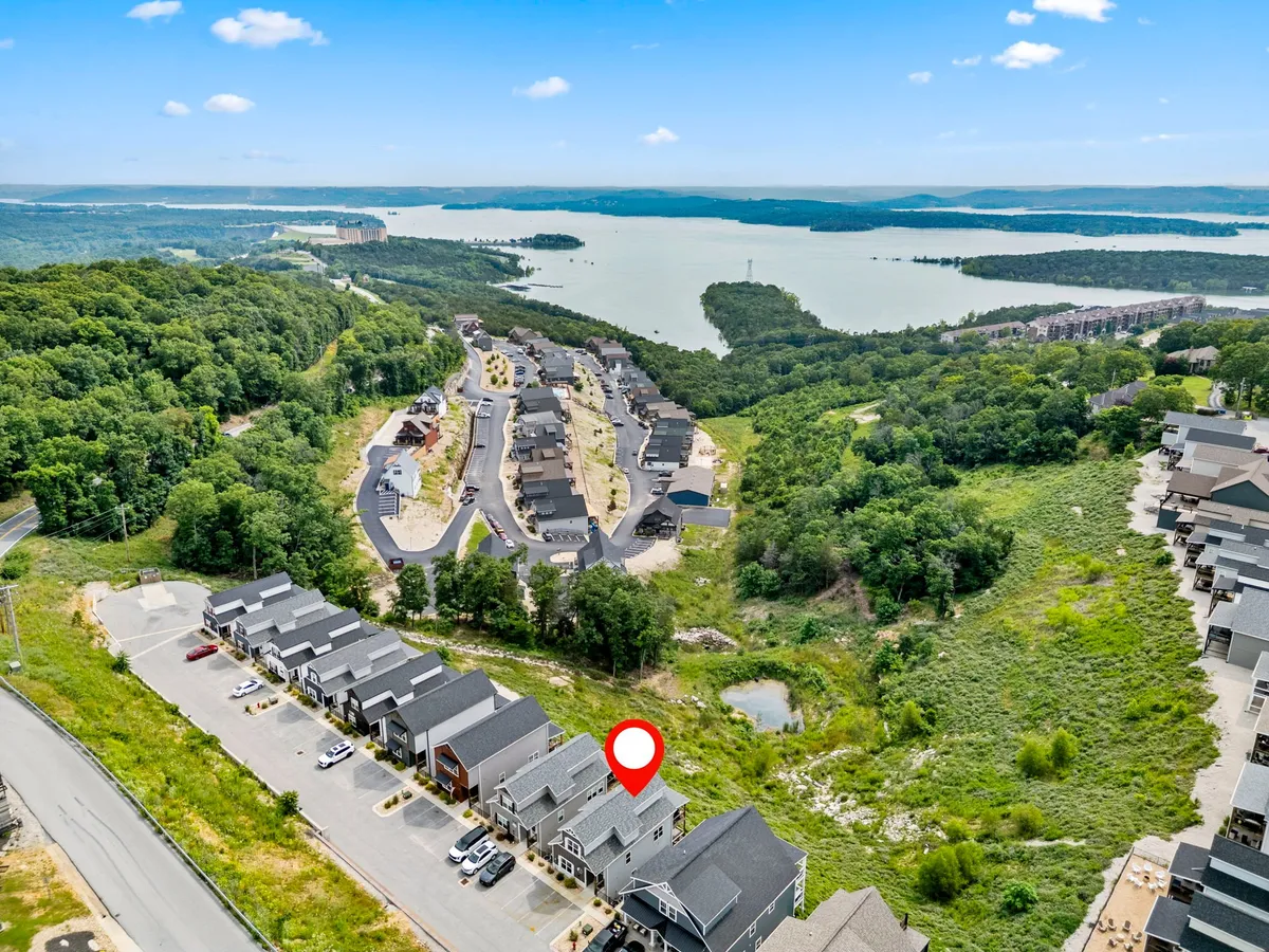A broad exterior shot showcasing Table Rock Lake in the distance, surrounded by verdant greenery and a well-designed housing development. The scene is peaceful, offering a sense of nature and community living along the lakeshore.