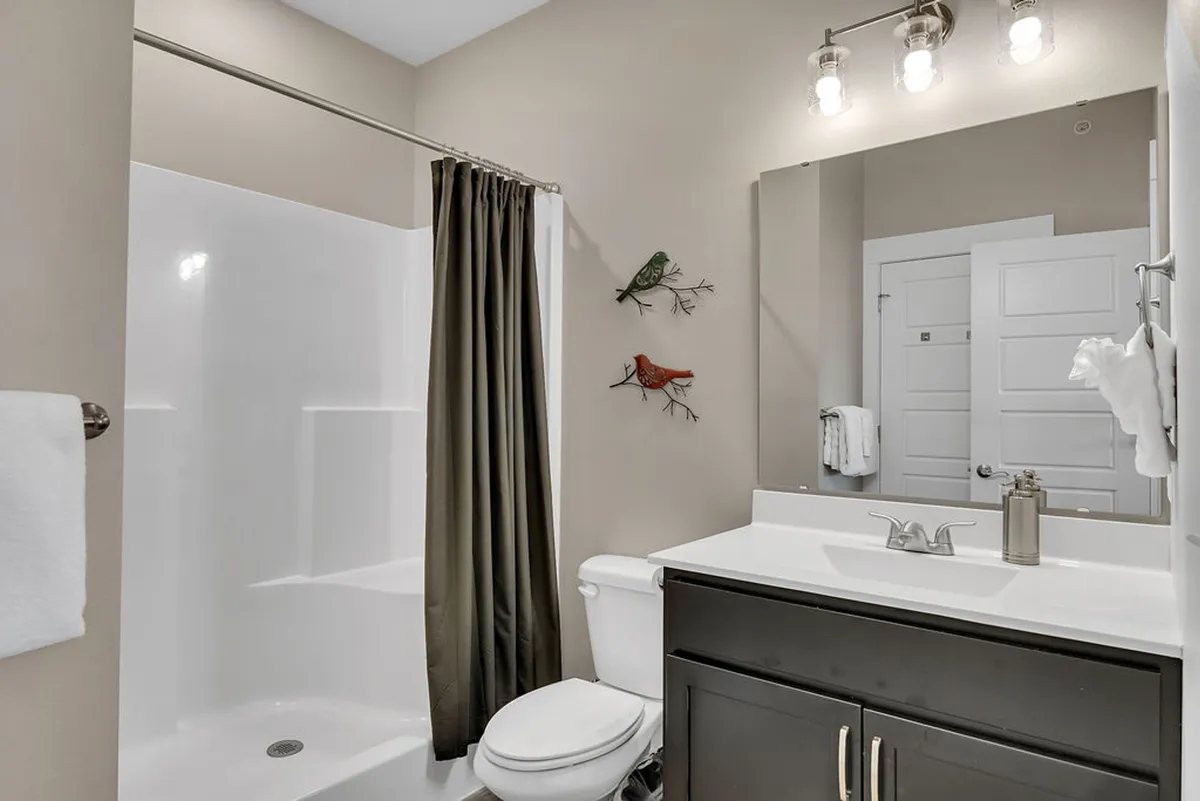 A sparkling clean bathroom featuring a vanity sink, mirror, and a modern step-in shower, complemented by decorative bird accents. The space feels refreshing and inviting, ideal for unwinding with a relaxing shower or morning routine.